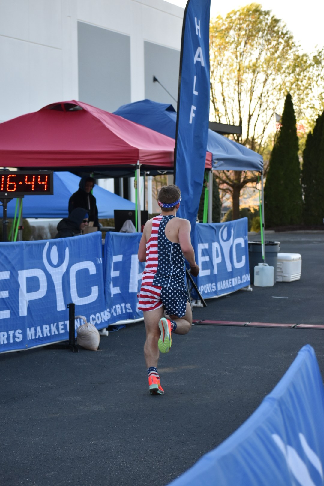 A runner crosses the finish line at the Wildman race in Mooresville, NC, framed by Epic Sports Marketing banners with the race clock overhead